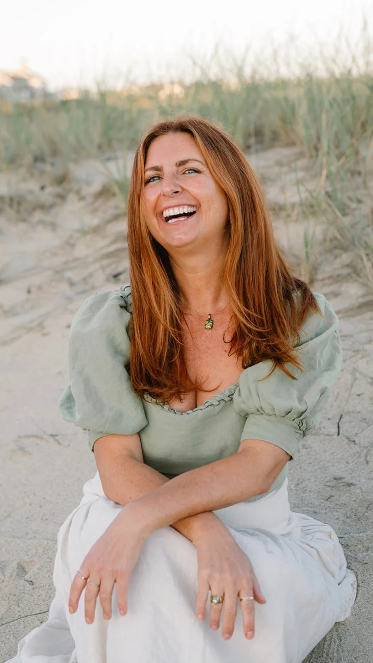 Christina Trifero laughing, seated in the sand dunes