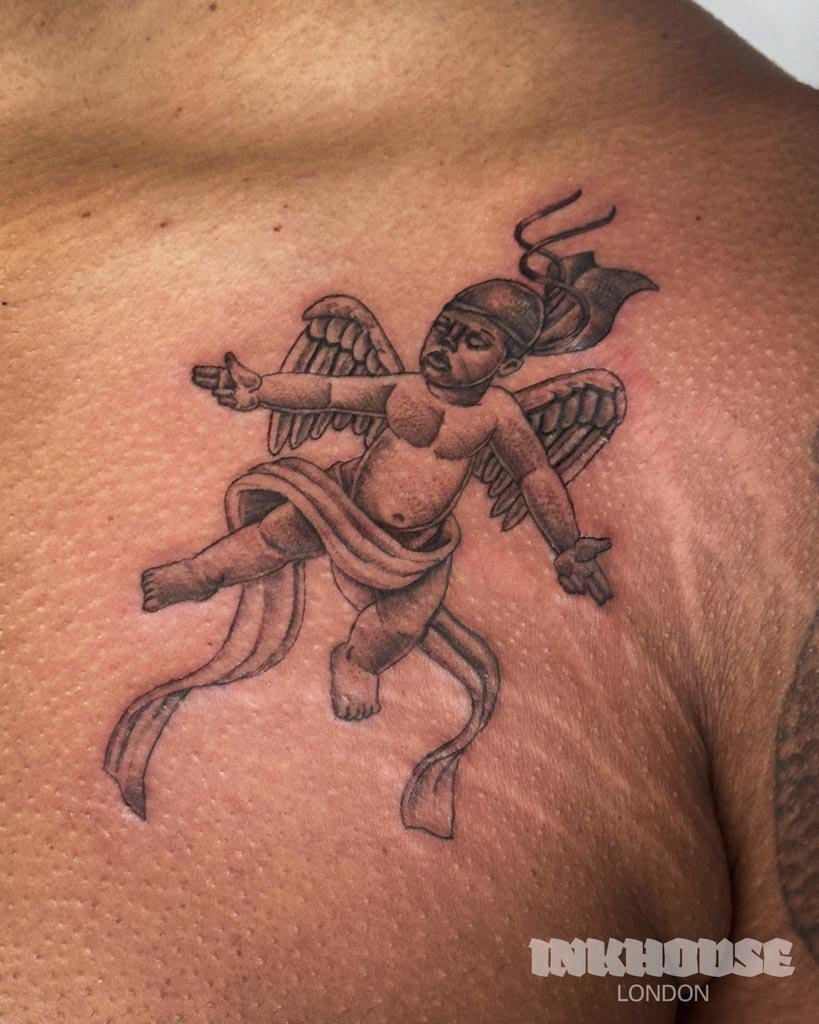 Tattoo of a flying cherub on a person's shoulder