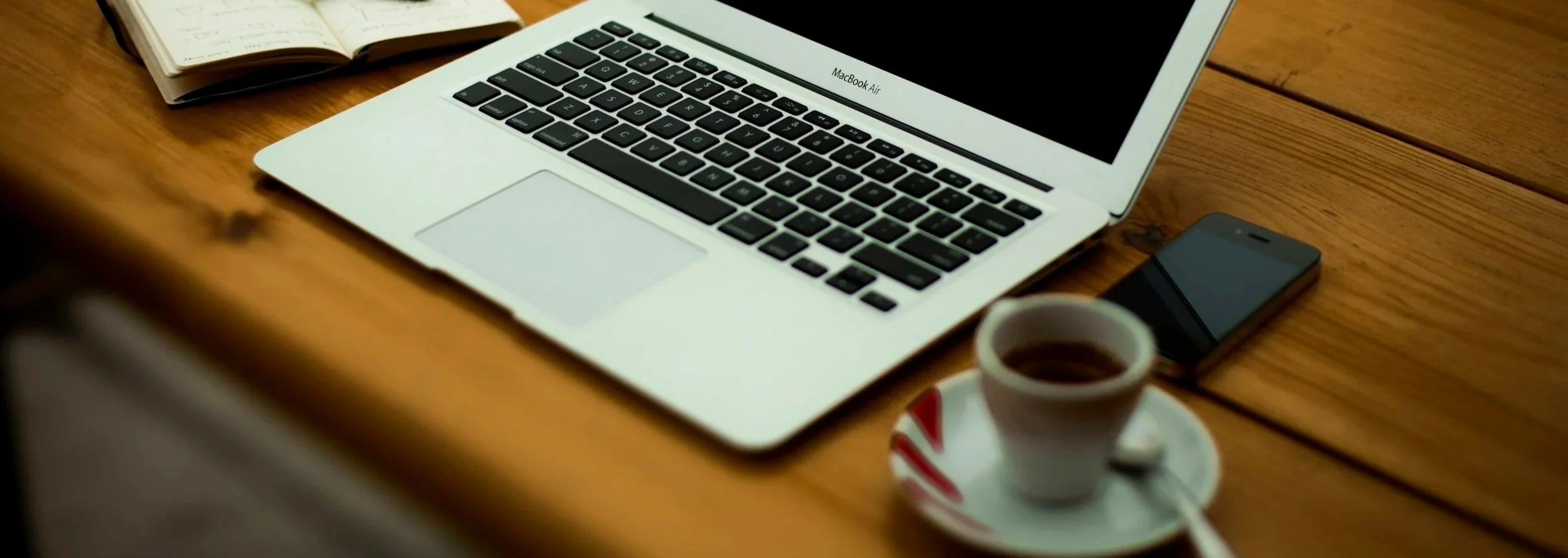 Close-up on a photo of a laptop, coffee mug, and cell phone