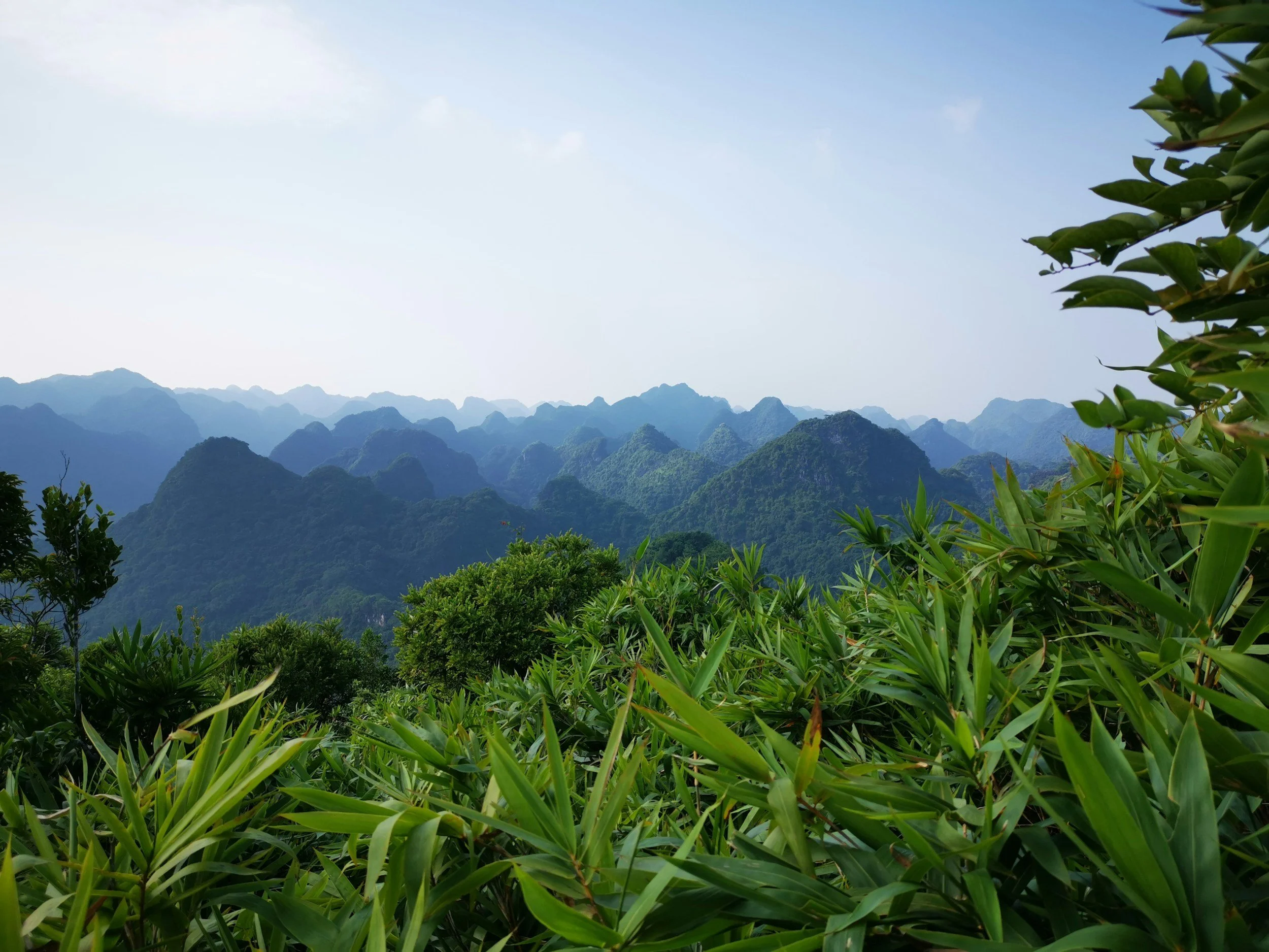 Lush green mountain landscape with multiple peaks under a partly cloudy sky.