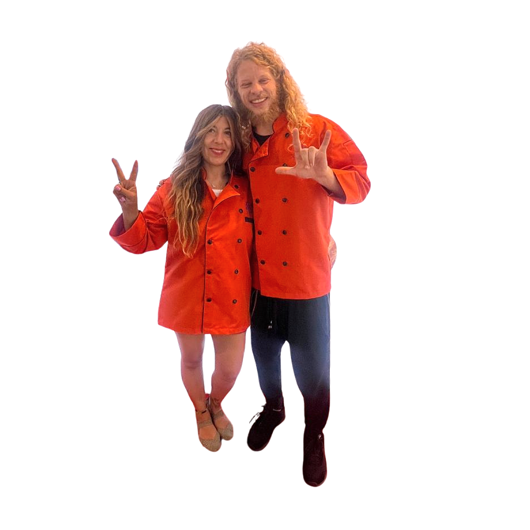 Two people in orange chef jackets posing with peace signs and making rock and roll hand gestures, on a white background.