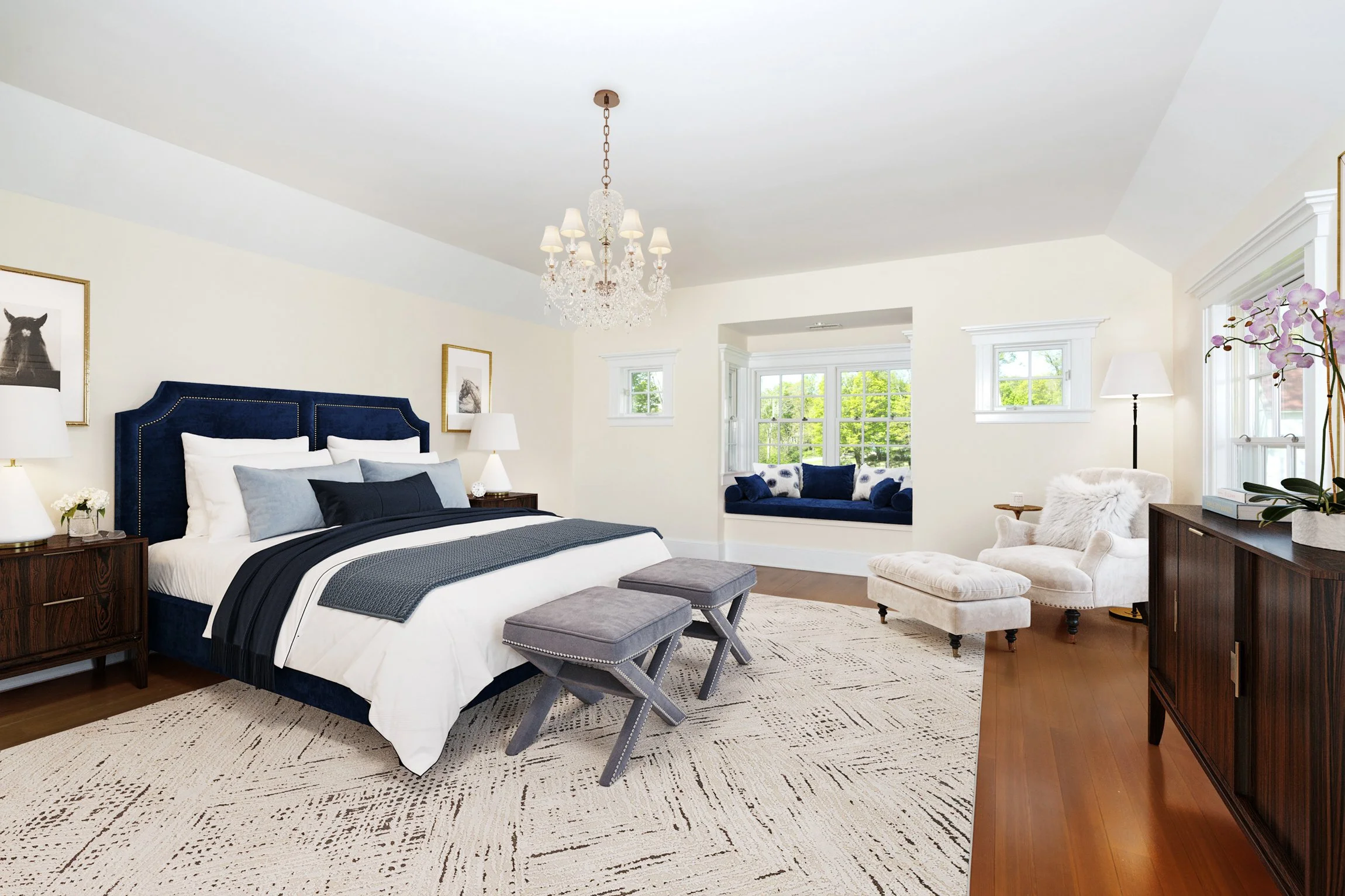 Spacious bedroom with a large bed, two ottomans, a sitting nook, and a plush armchair, featuring a chandelier and multiple windows for natural light.