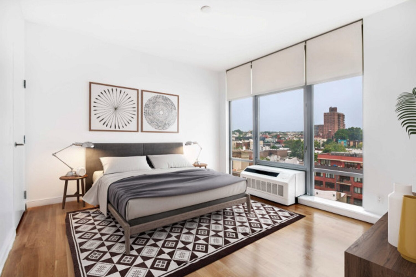 Modern bedroom with large window, white walls, wooden floor, black and white bedding, two bedside lamps, and abstract wall art.