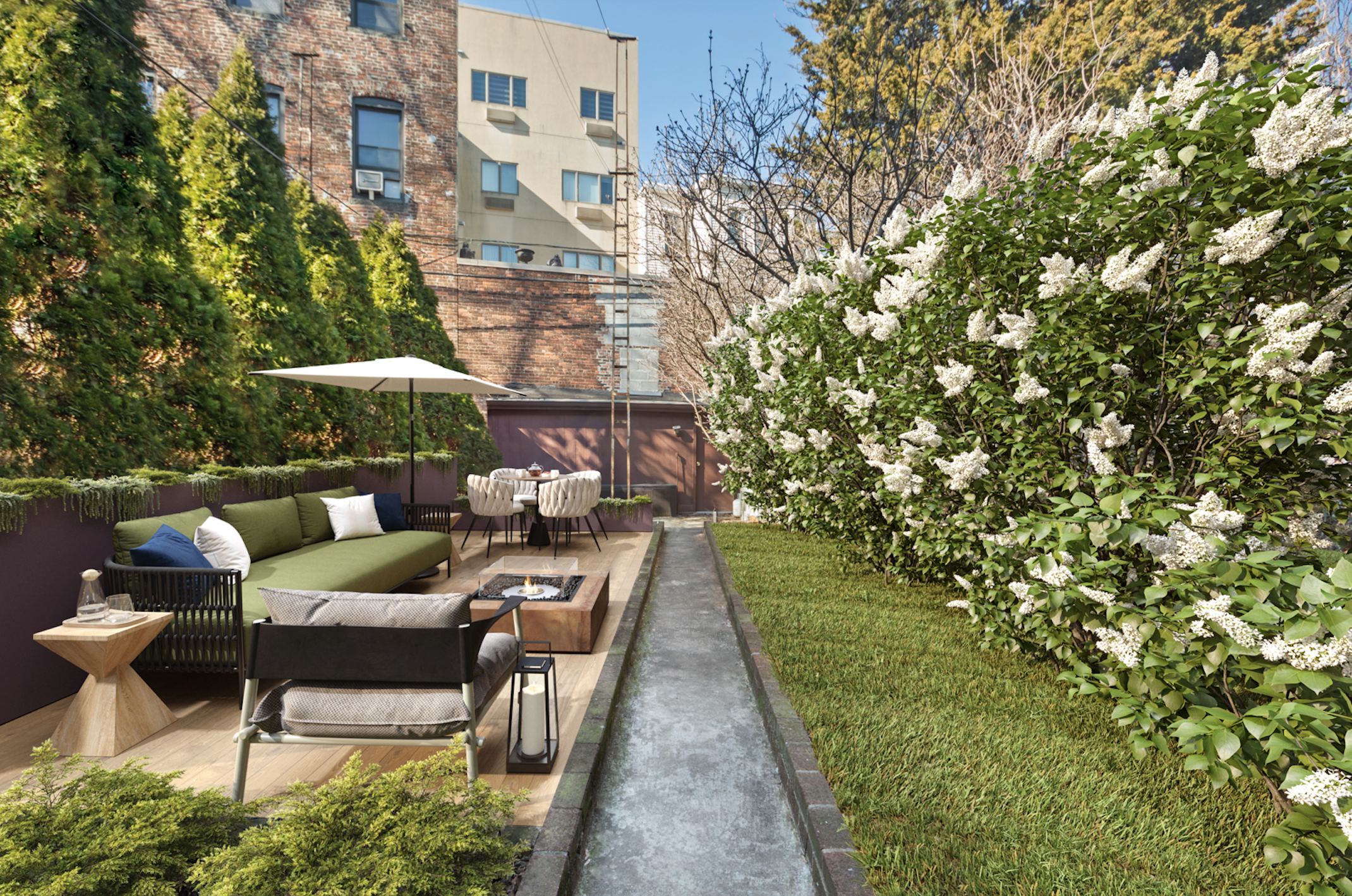 Urban backyard garden with a patio area, outdoor furniture, a table with chairs, an umbrella, a fire pit, and flowering shrubs, surrounded by tall buildings.