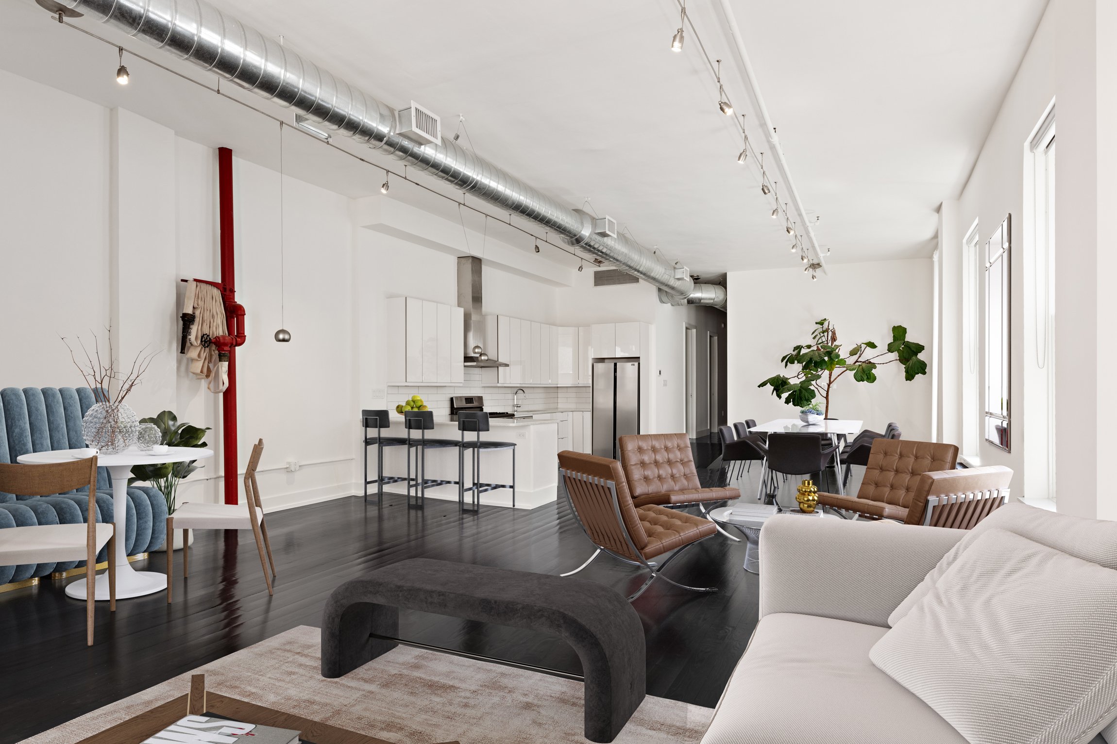Modern open-concept living space with white walls, dark hardwood floors, and large windows. Features a white kitchen area with black bar stools, a dining table with black chairs, and a seating area with a white sofa, brown leather chairs, and decorat