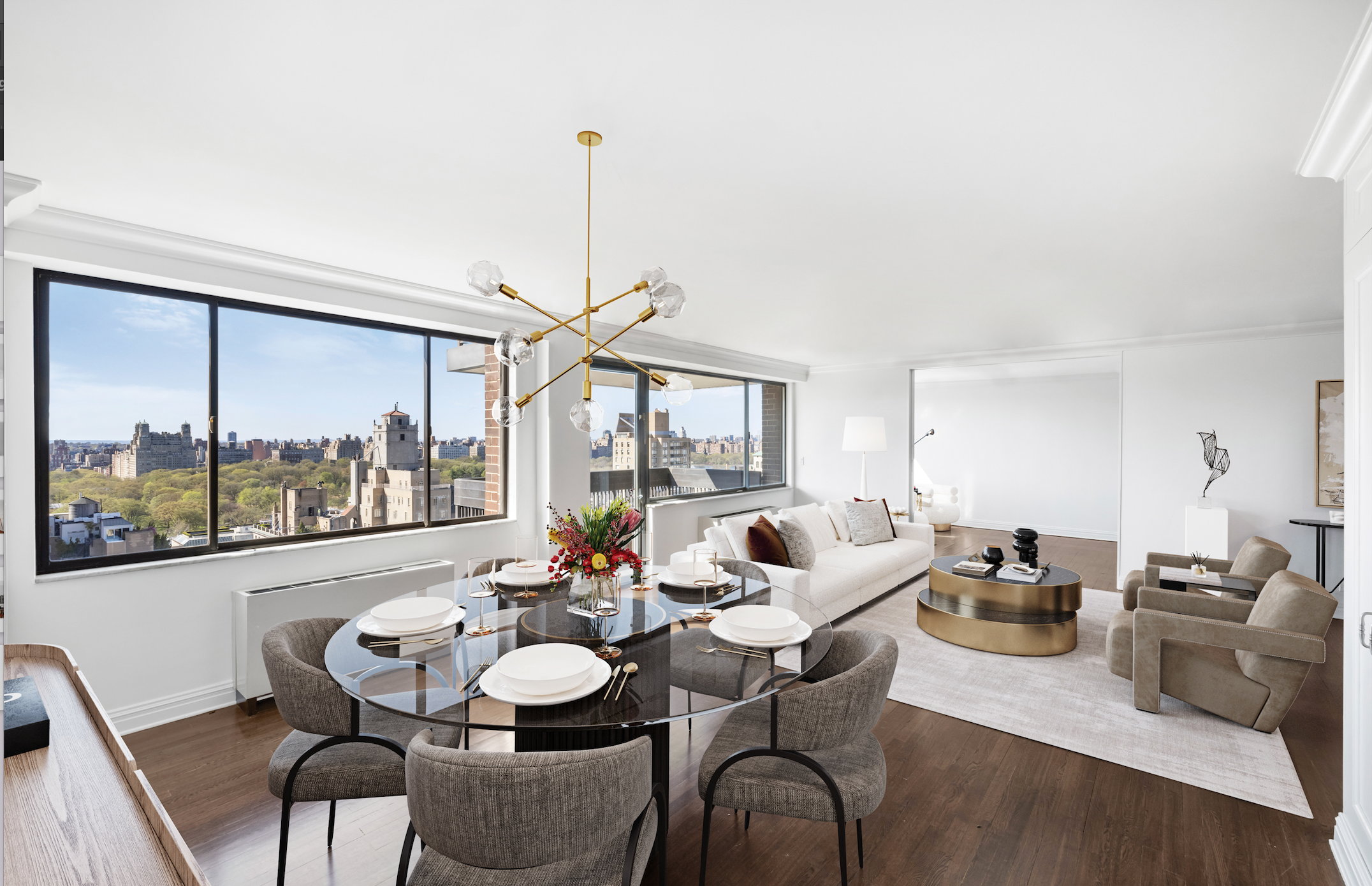 Modern living room with large windows, a round dining table set for six with grey chairs, a white couch, beige armchairs, a gold coffee table, and a cityscape view