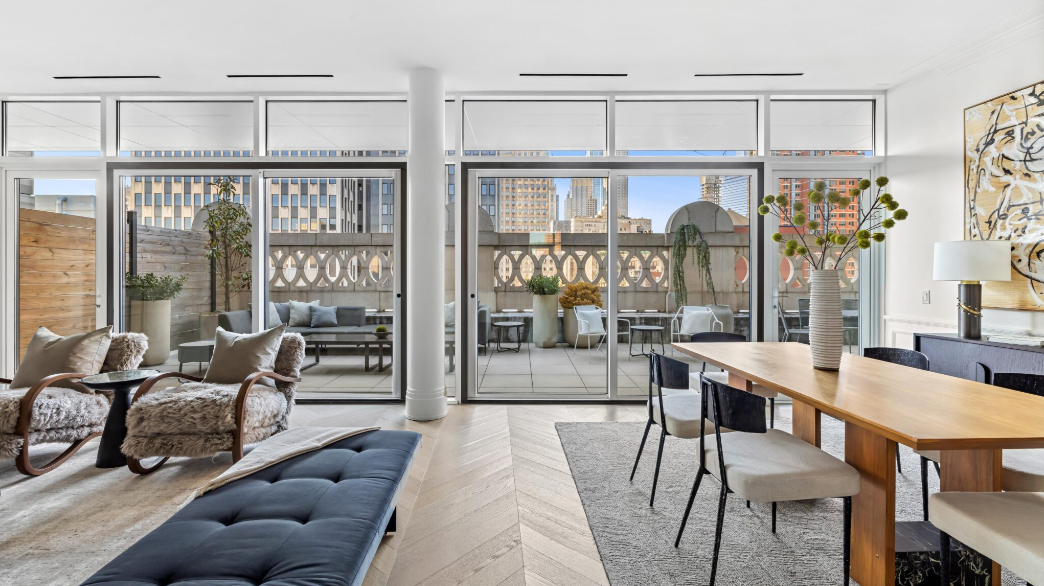 Modern apartment living room with large glass doors leading to balcony, stylish seating, wooden dining table with chairs, decorative vases, and cityscape view.
