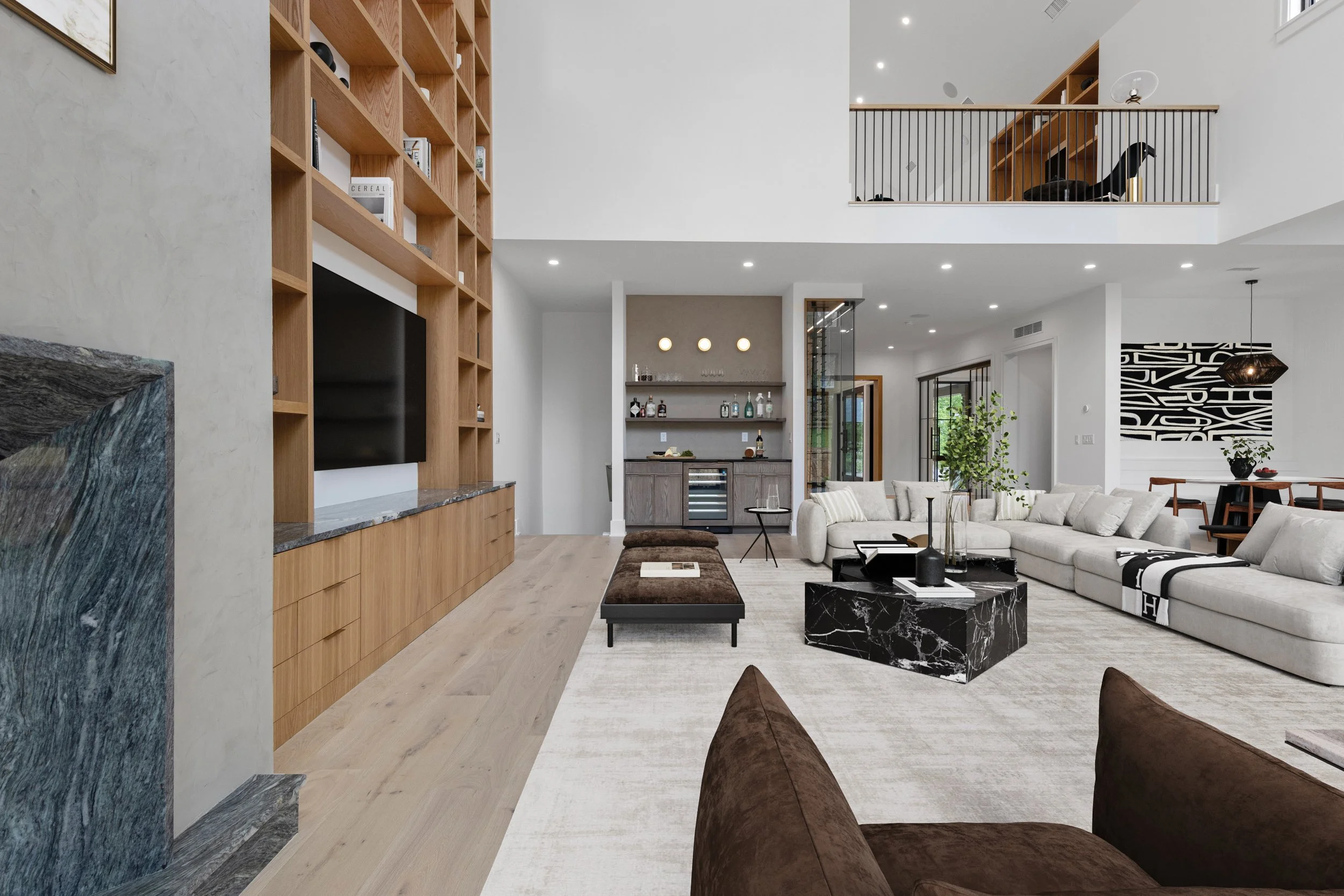 Modern living room with beige sectional sofa, black marble coffee table, and wooden built-in shelving with TV.
