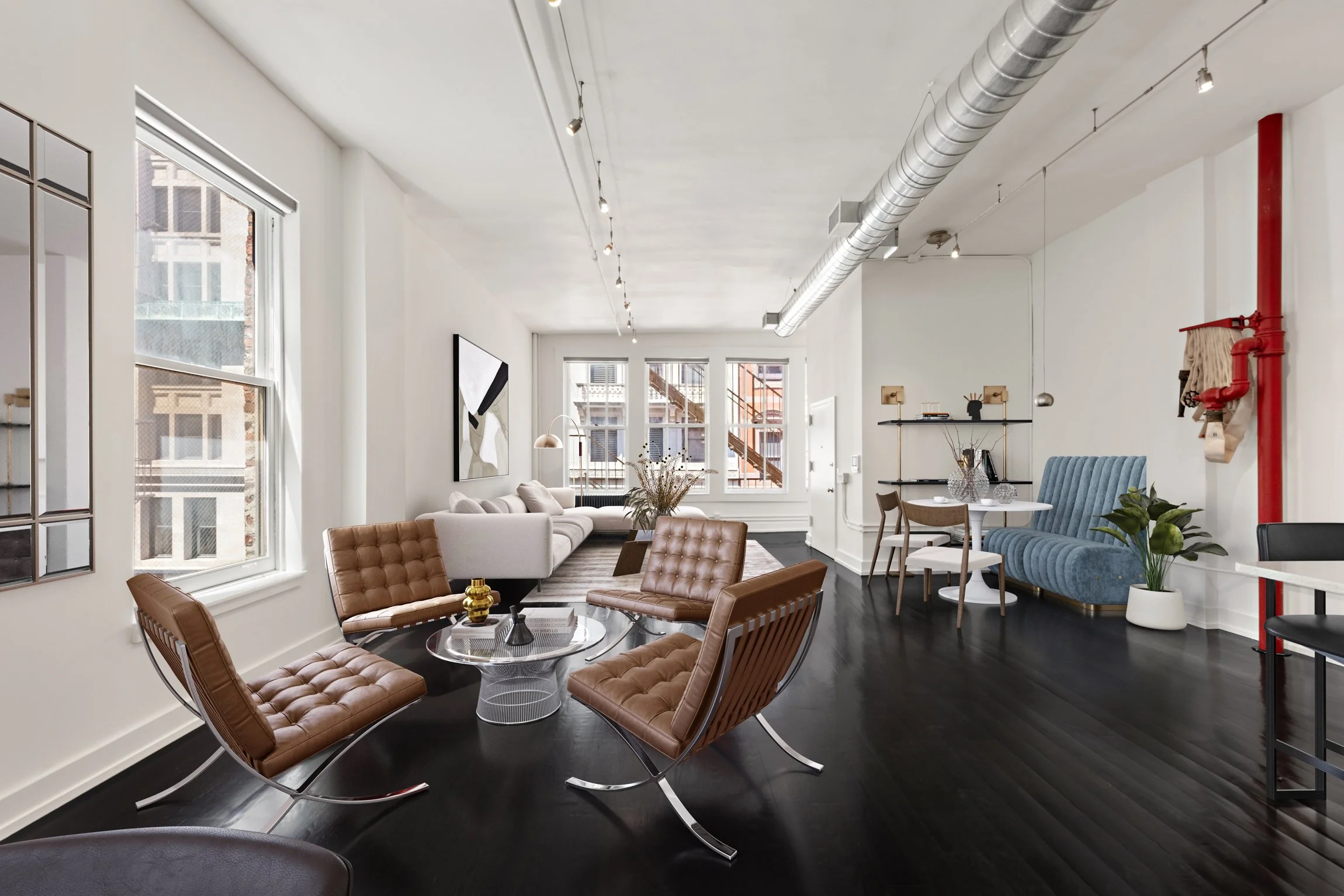 Modern living room with white walls, large windows, a white couch, brown leather chairs, black flooring, and minimalist decor.