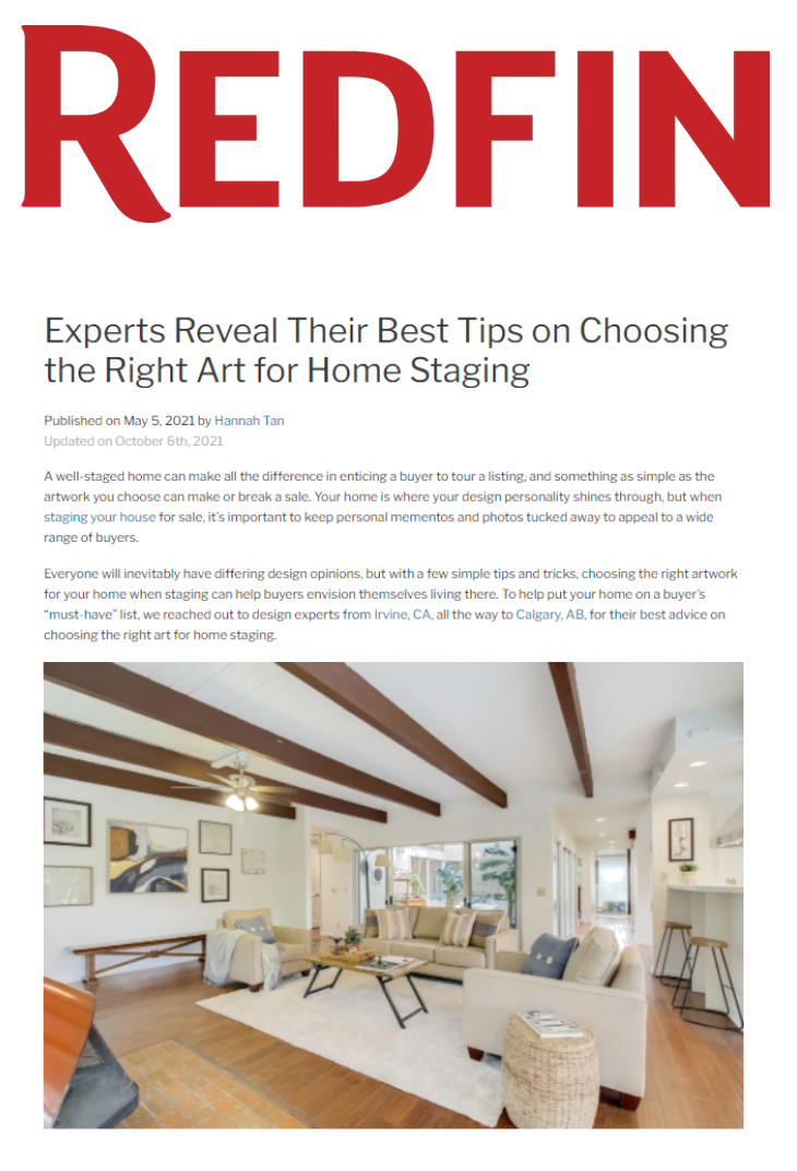 Living room with white walls, wooden beams on ceiling, large windows, beige sofa, armchairs, coffee table, art on walls, and decor.