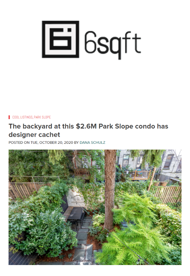 A backyard with lush green foliage, trees, and a stone pathway in a residential area.