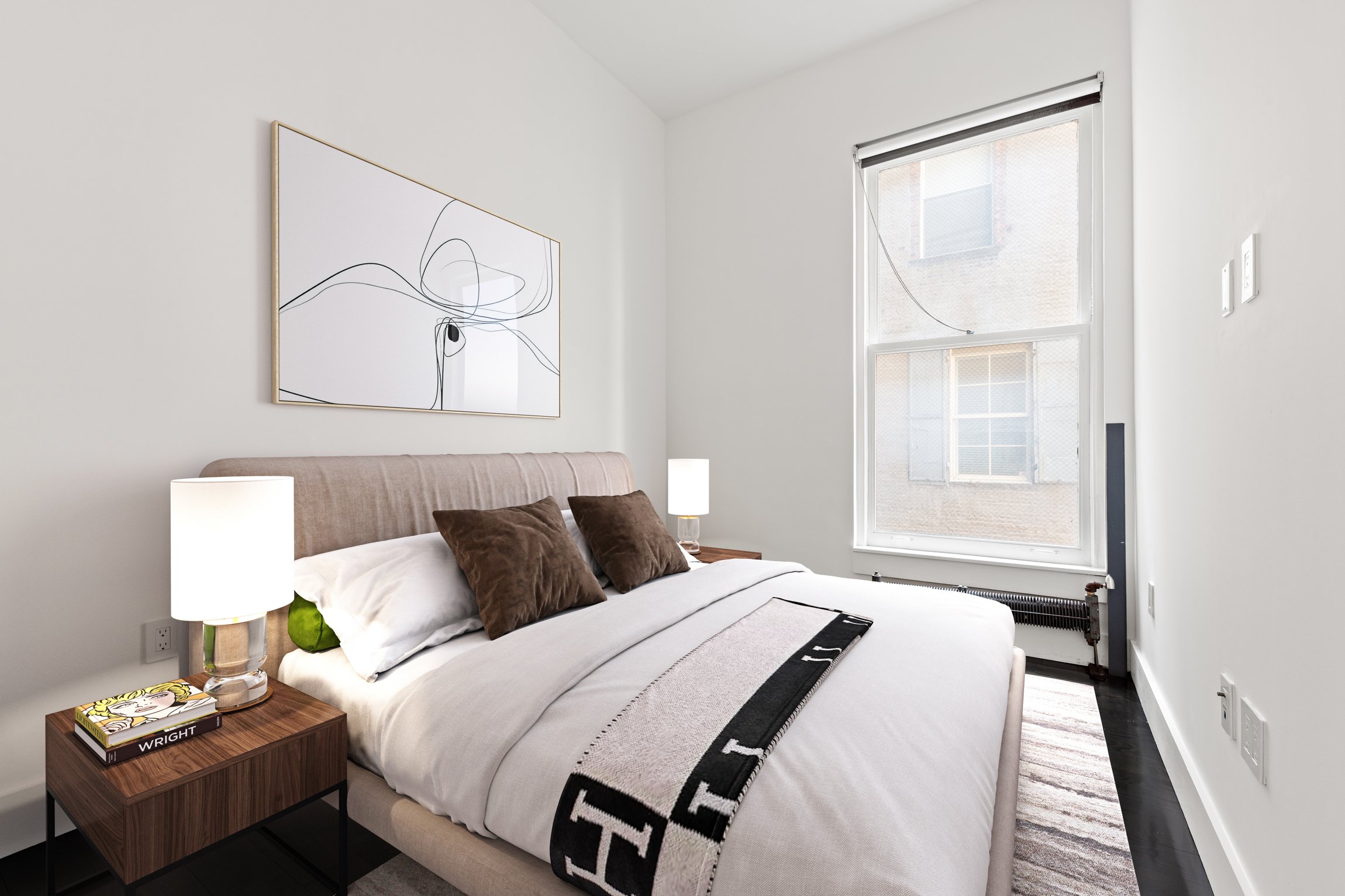 A modern bedroom with white walls, a bed with white bedding and brown pillows, a wooden nightstand with a lamp and a book titled 'WRIGHT', and a large abstract art piece above the bed. There is a window with a partially rolled-up blind letting in nat