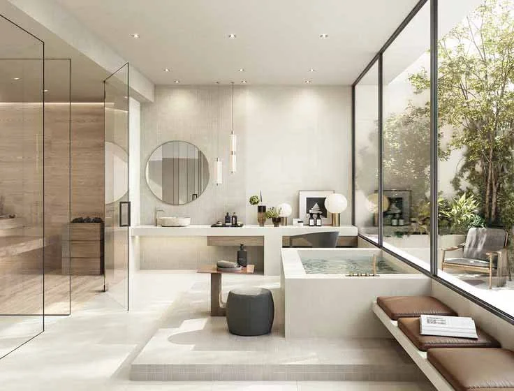 Modern bathroom with a large glass window overlooking a garden, featuring a built-in bathtub, a vanity area with mirror, and seating with magazines.