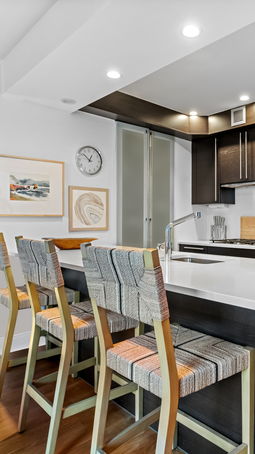Kitchen island with blue/ gray and sandalwood textured stools and warm toned artwork on the wall