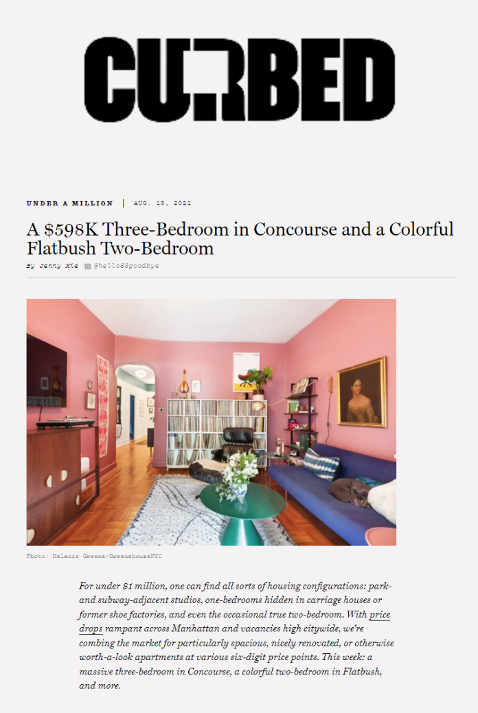 Colorful living room with pink walls, blue sofa, bookshelf, paintings, and a coffee table with flowers.