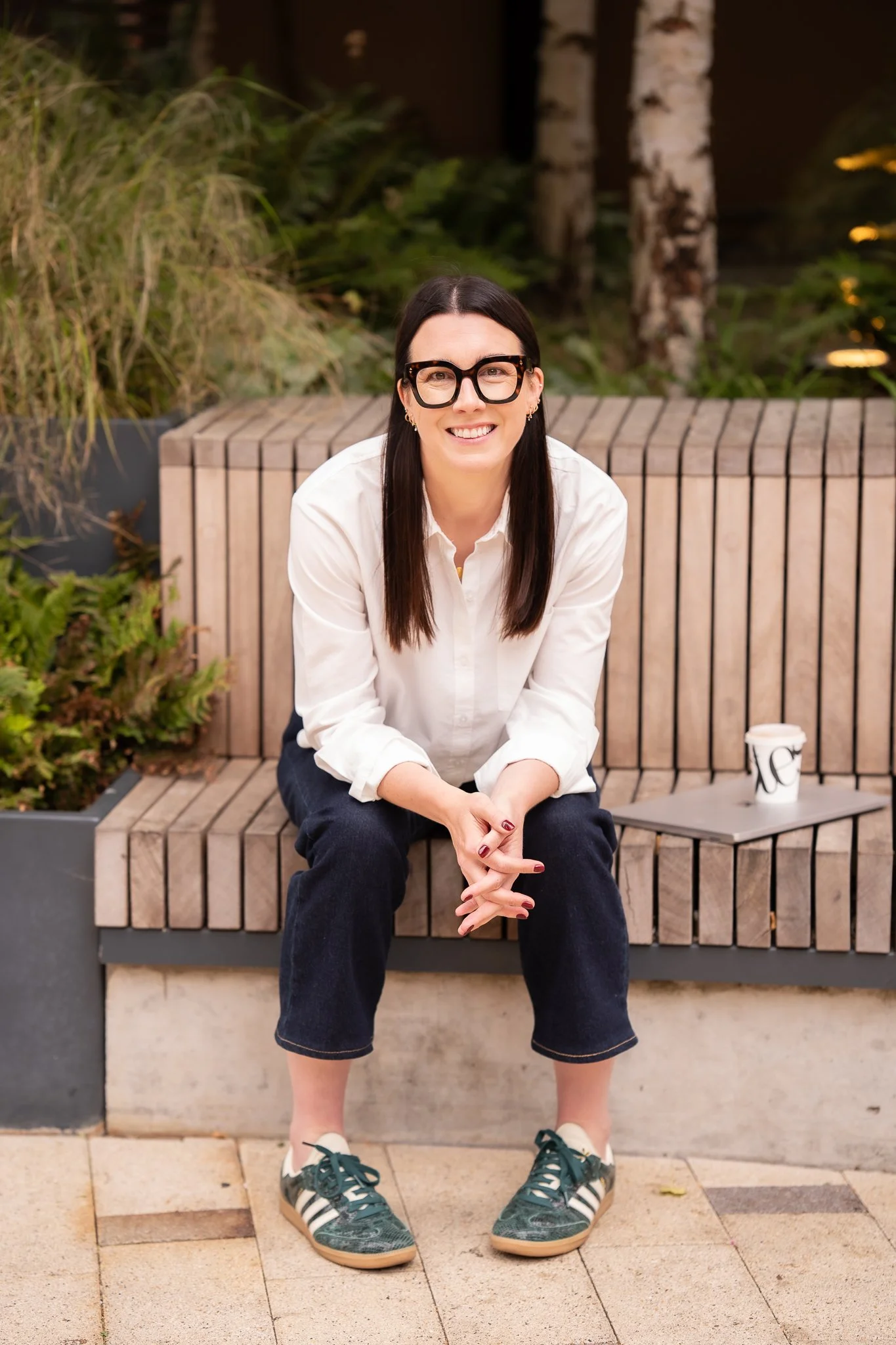 Harriet sat on a wooden bench with her laptop and coffee beside her
