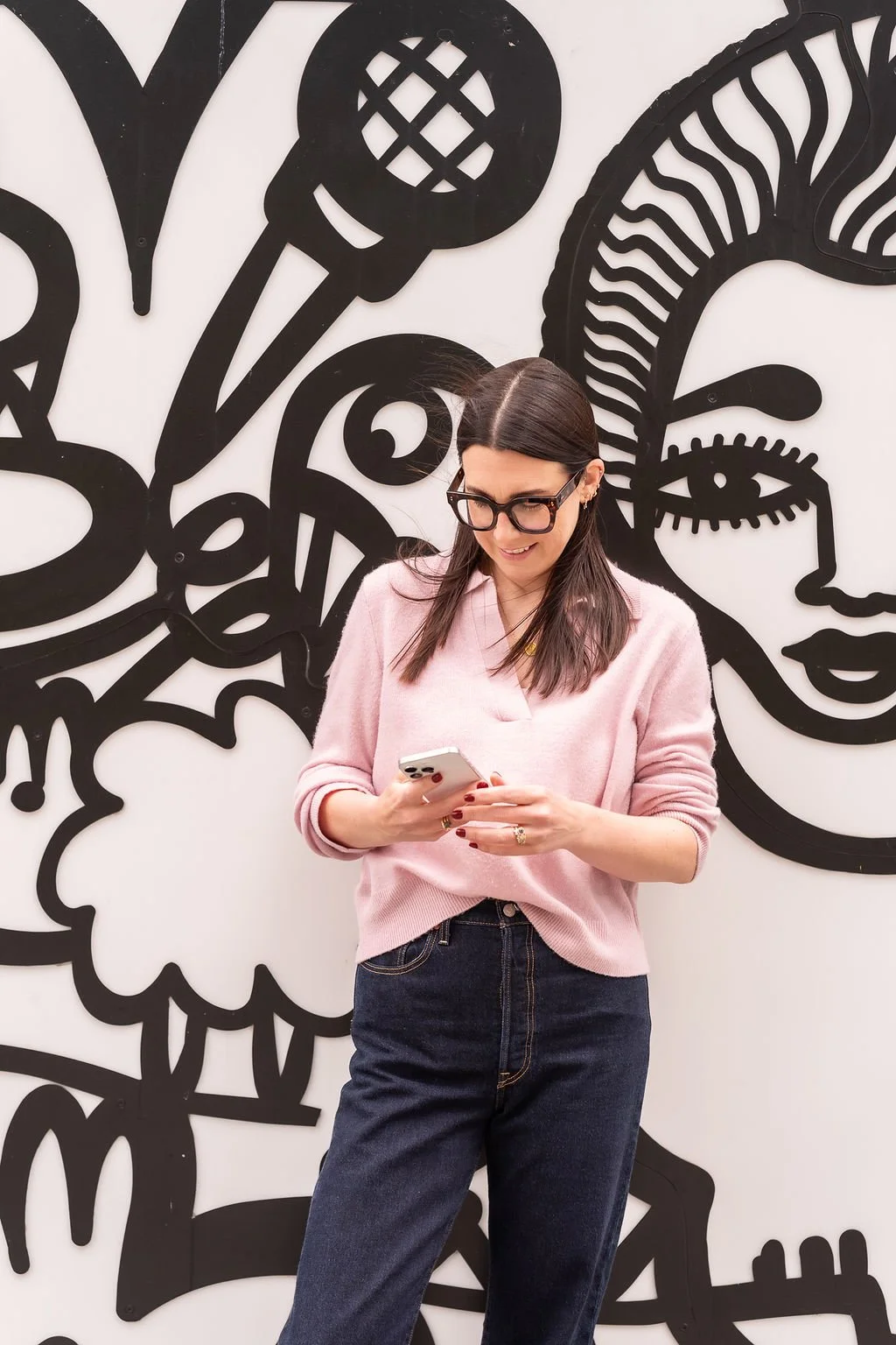 Harriet Cox stood against a graffiti wall looking at her phone