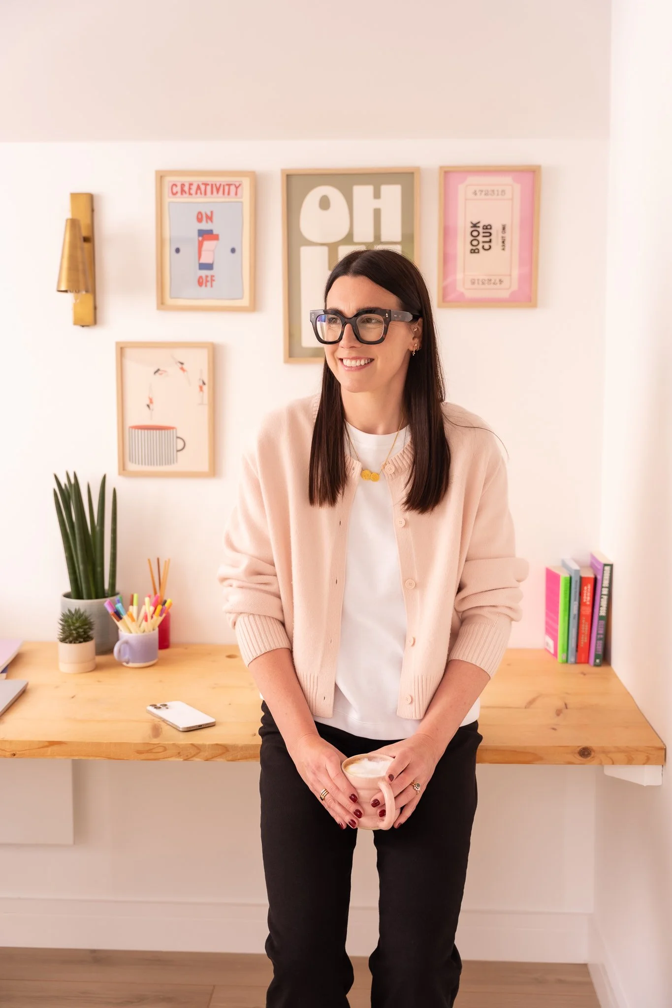 Harriet in her colourful office holding a coffee and smiling