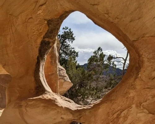 Natural circle hole in a rock formation with view of trees and sky