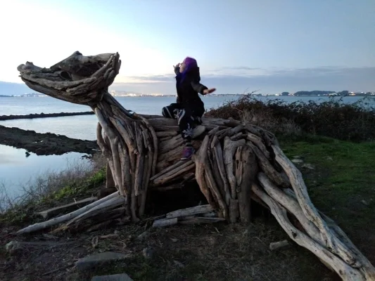 Person sitting on a large wooden dragon statue
