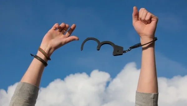 Two hands in the air breaking off handcuffs