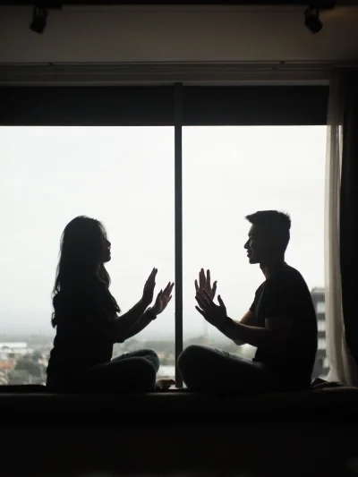 Silhouette of couple sitting in front of window clapping hands