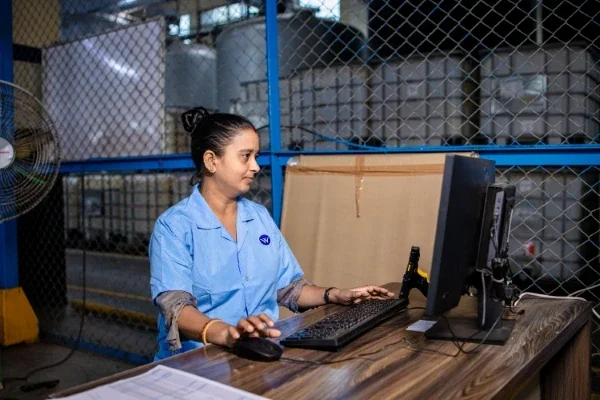 Woman standing at a computer in an industrial workplace setting
