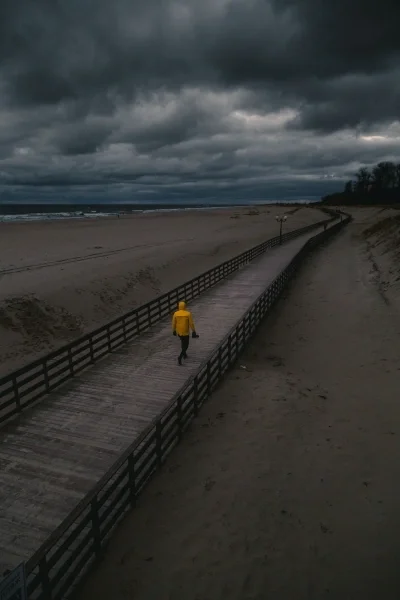 Person walking on beach boardwalk on gray day