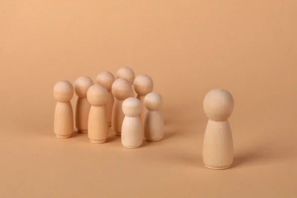Group of wood blocks resembling people with one offset away from the group