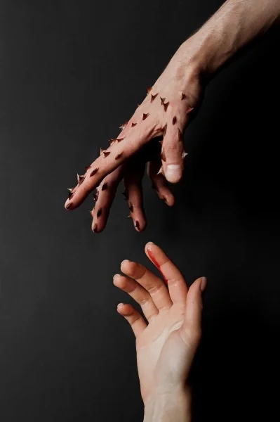 Close up of 1 hand with sharp points and another with blood