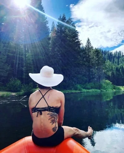 Person sitting on raft on lake looking towards sun