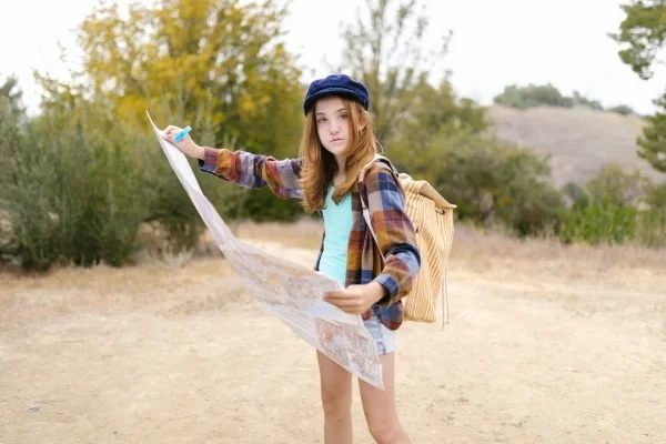 Girl outside with backpack holding a map