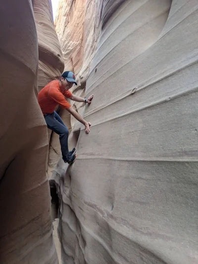 Person climbing up walls in a slot canyon