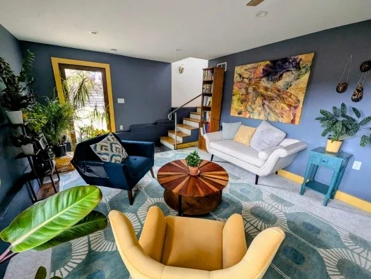 Colorful room with sofa, two chairs, and a circular wooden table