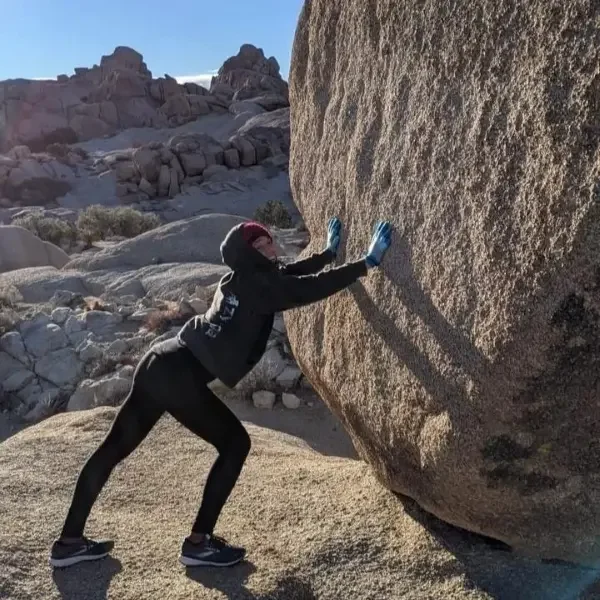 Woman pushing on giant boulder with two hands