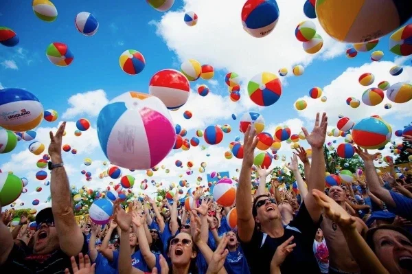 Large gathering of people throwing beach balls in the air