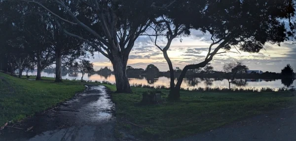 Sunset on cloudy day with water and trees in foreground