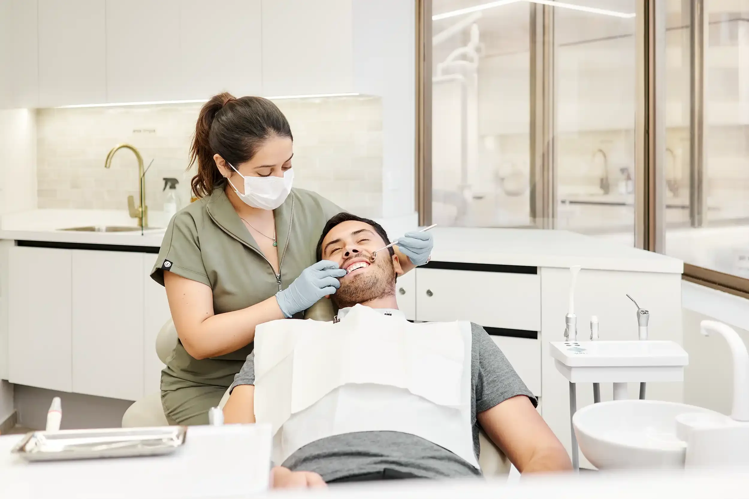 Dentista en Providencia, diagnóstica a paciente hombre sonriente para limpieza dental.