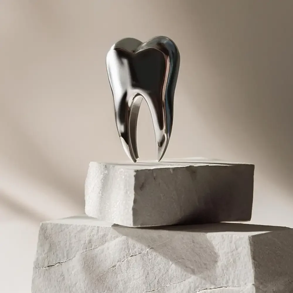 Diente metálico brillante sobre bloques claros, simbolizando el concepto de limpieza e higiene dental profesional en Clínica Aires, Providencia.