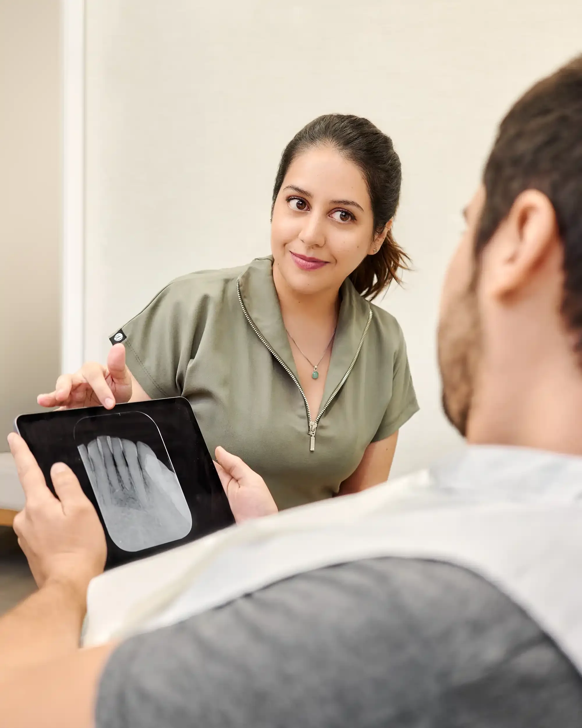 Dra. Paula Pinto, dentista especialista en tratamiento de conducto, mostrando radiografía dental en tableta a un paciente.