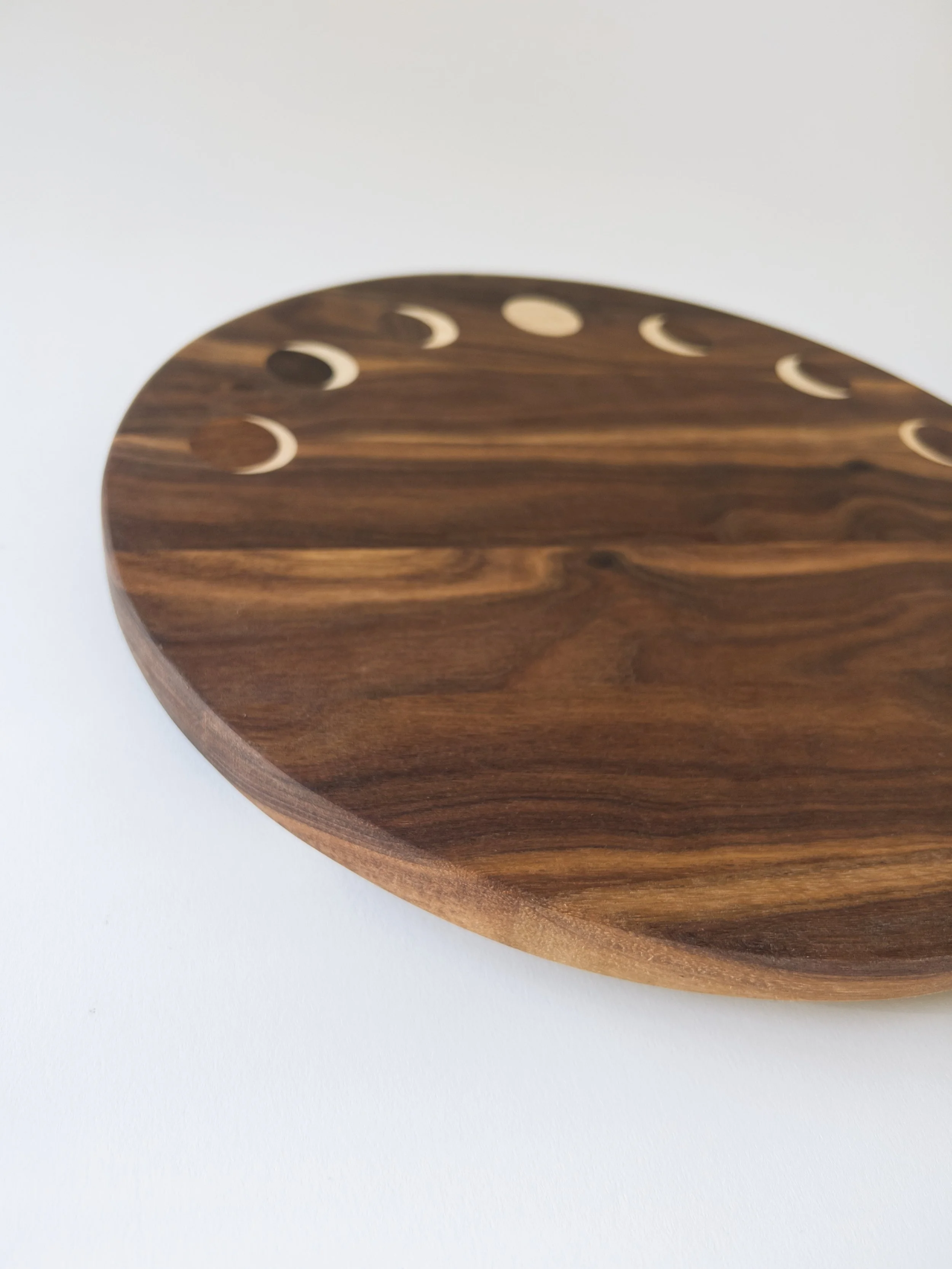 Handmade Eclipse serving board by Toryn Black Design, featuring contemporary design and the natural beauty of Appalachian hardwoods. Intricate moon phase inlay. Crafted in Western North Carolina, this distinctive wooden serving board is designed for 