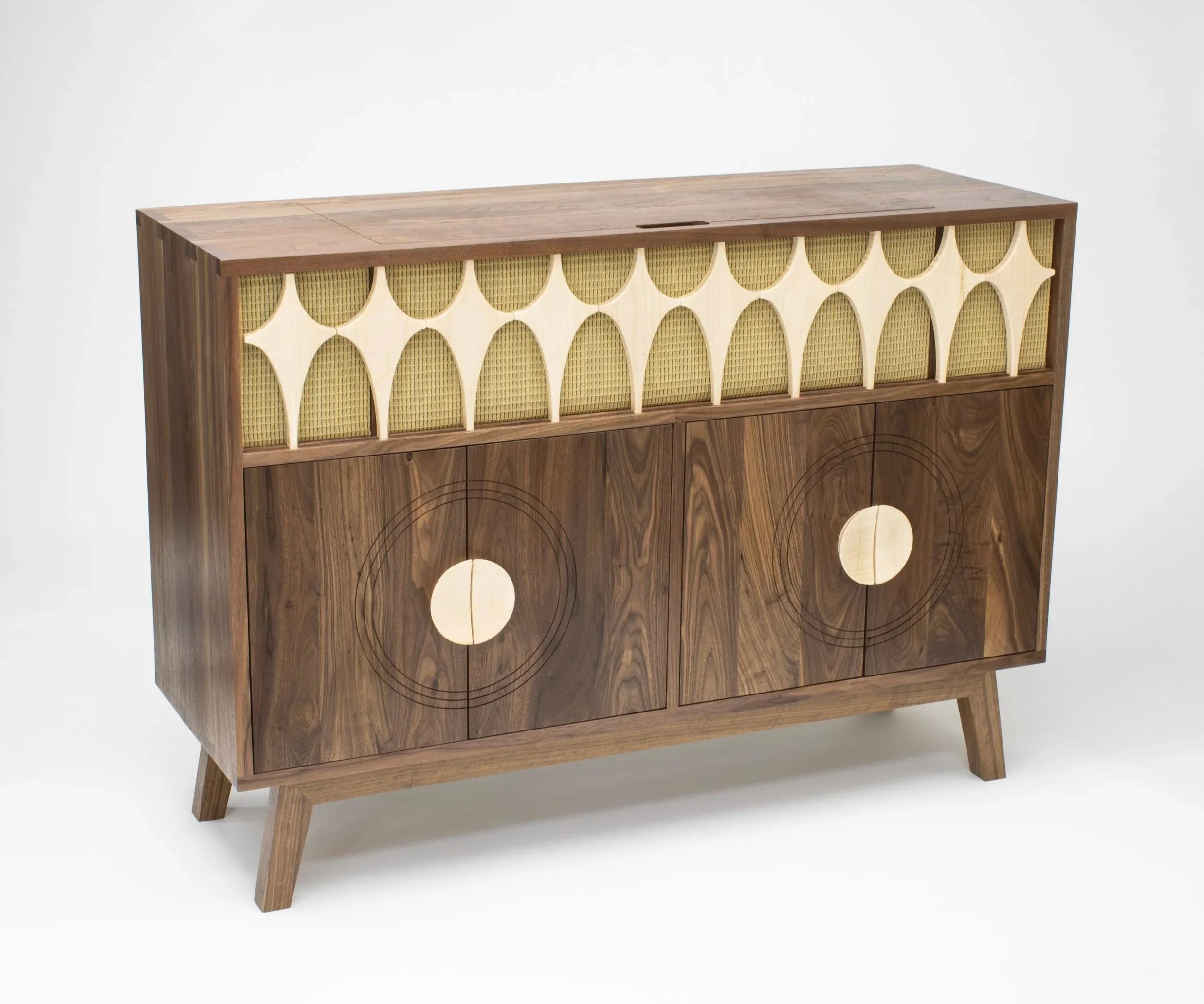 A handcrafted mid-century modern record cabinet made from walnut and curly maple, featuring sculptural details, star-shaped inlays, and vintage-inspired speaker fabric. Designed by Toryn Black Design in Western North Carolina, this custom Hi-Fi cabin