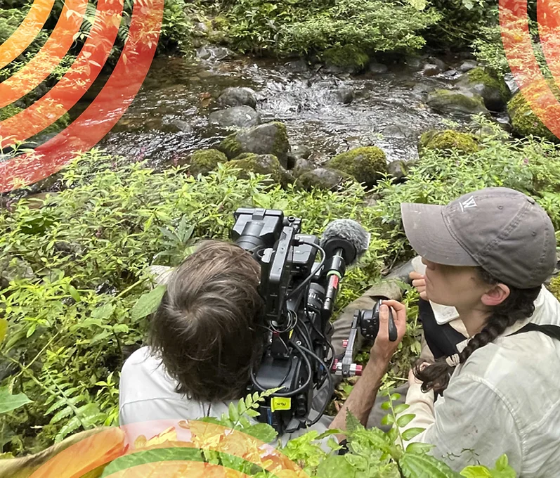 Two film makers beside a river on a mountain.png