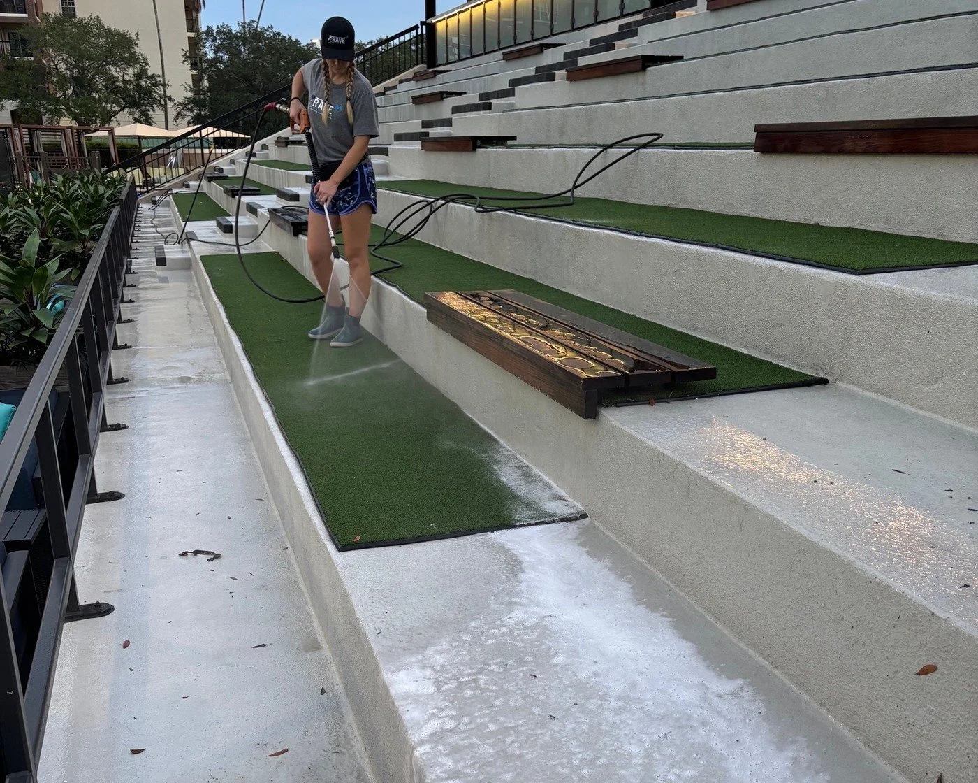 RAVE Power Wash team member pressure washing concrete seating at a commercial fitness property