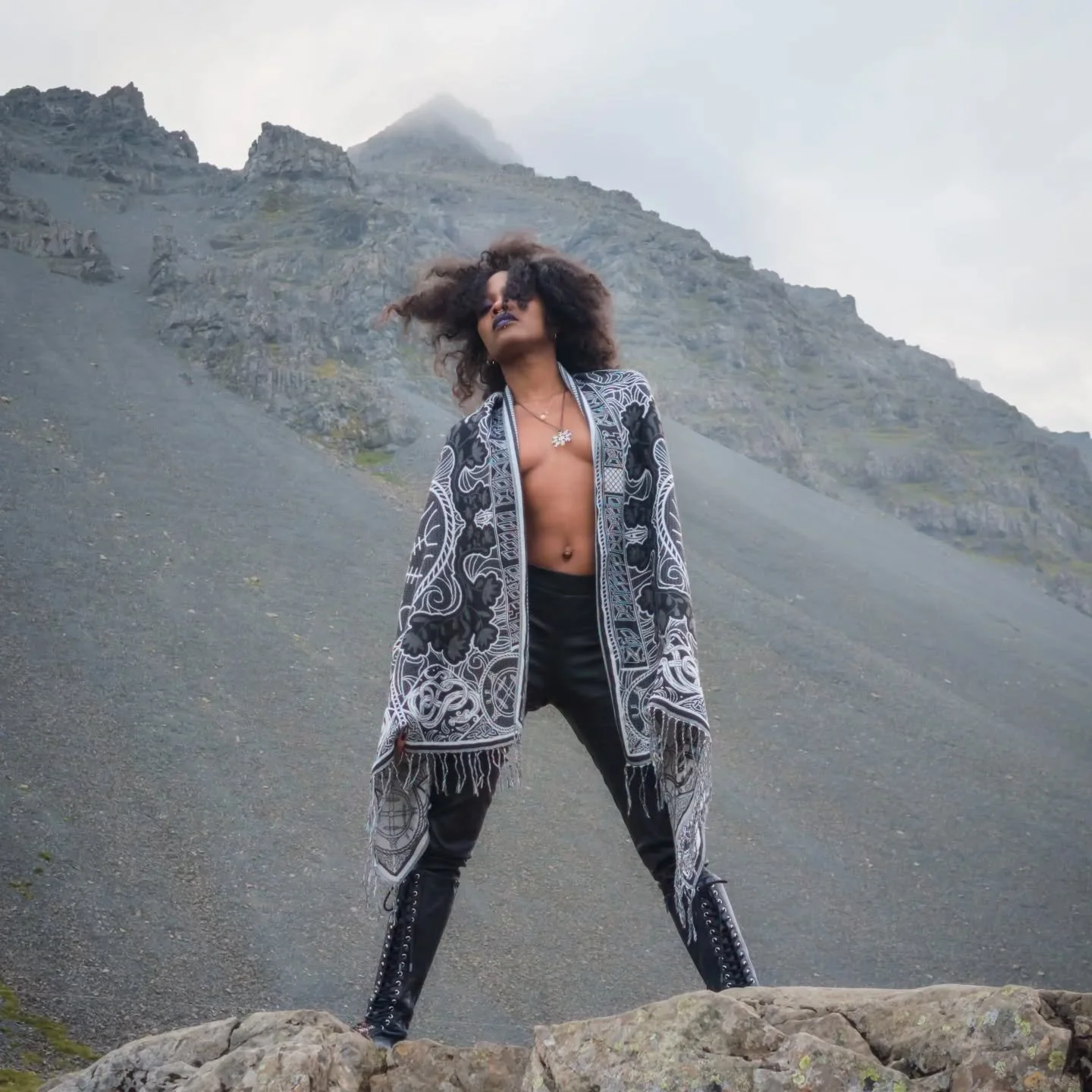 @blackmagickbarbie at Krossnes &mdash; wrapped in the Wanderer&rsquo;s Scarf, where the magic is thick and the wind speaks old names. East Iceland holds its secrets close. She walks through them like she belongs.
#WanderersScarf #Krossnes #IcelandMag