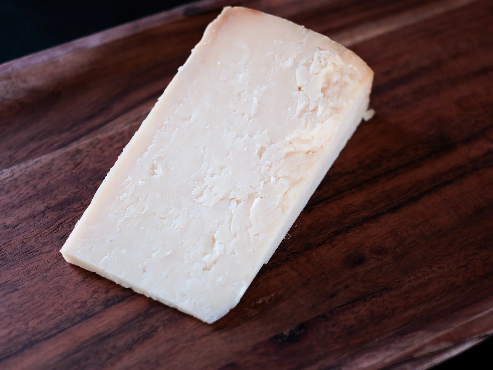 a wedge of cabot clothbound cheddar sits on a board