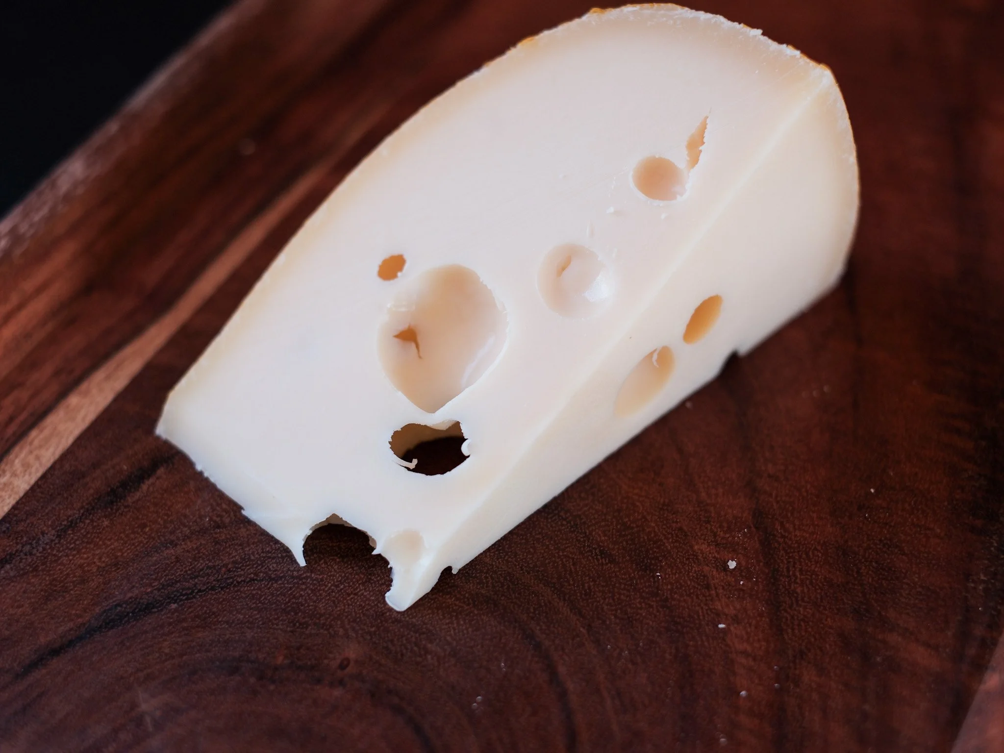 pieces of golden swiss by oakdale cheese sits on a dark wood board