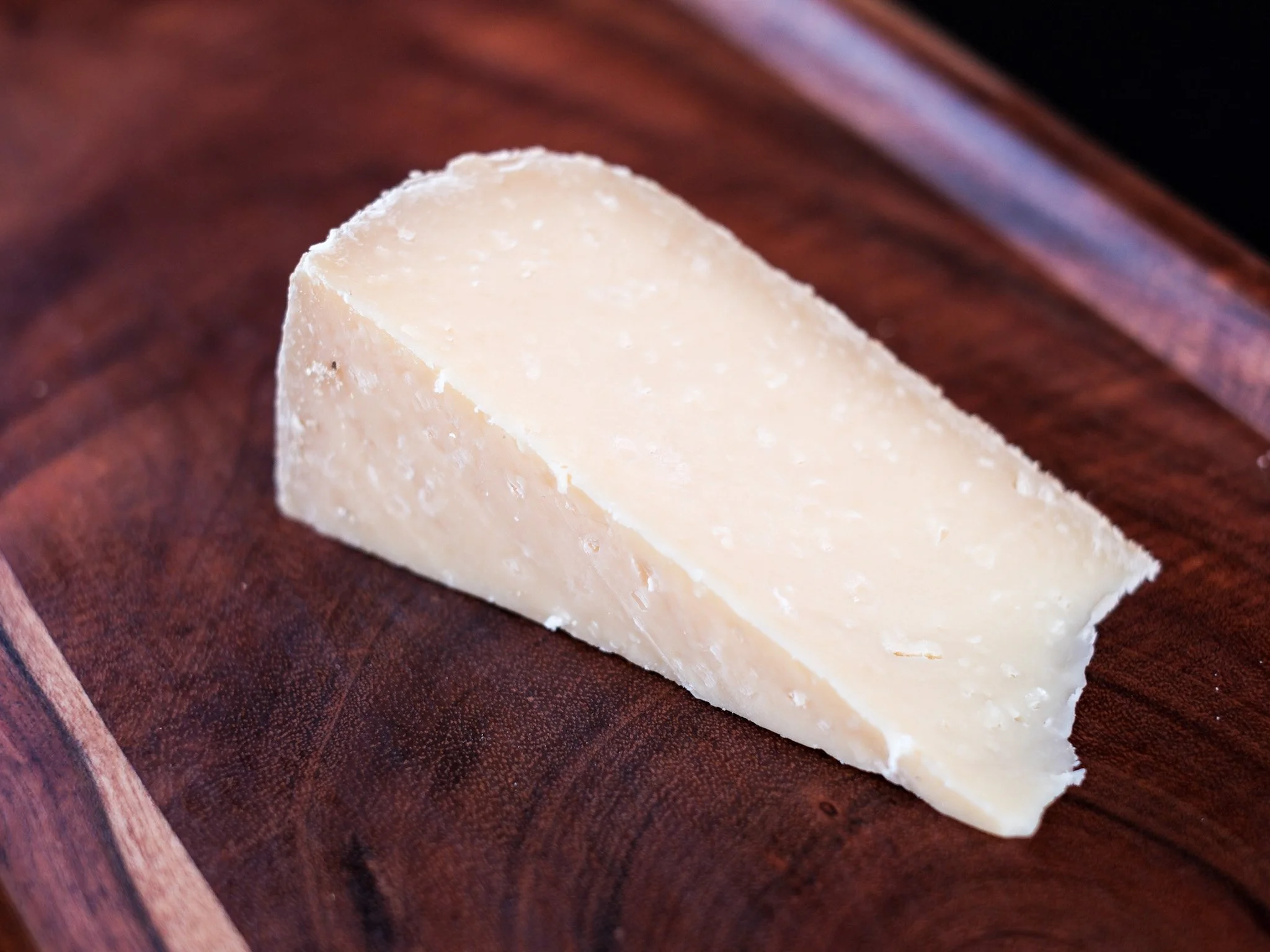 wedge of of east of edam sits on a wood board