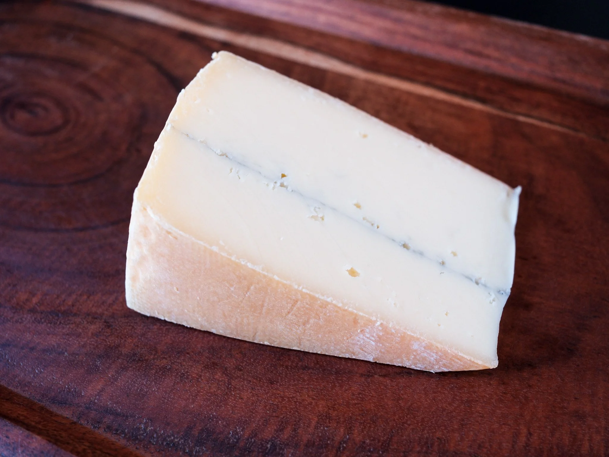 a piece of ashbrook cheese sits on a wood board.