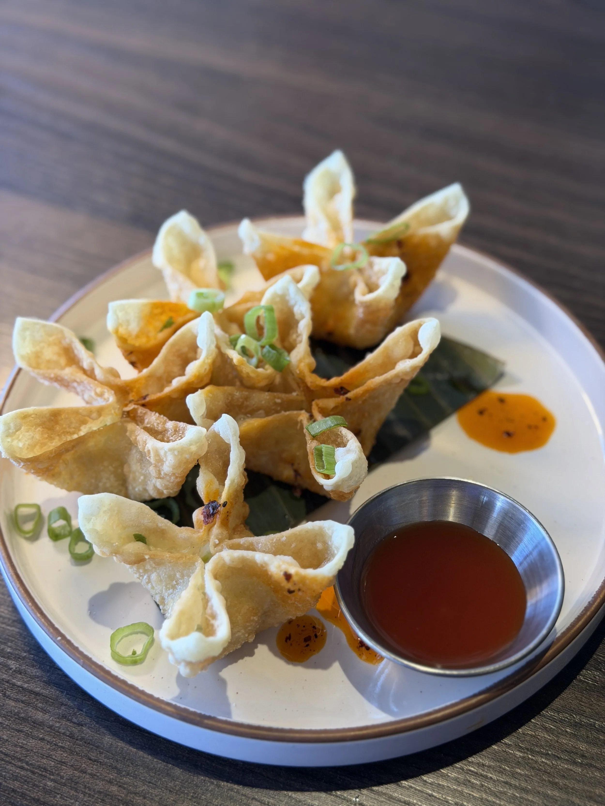 five pieces of crab rangoon sit on a white plate